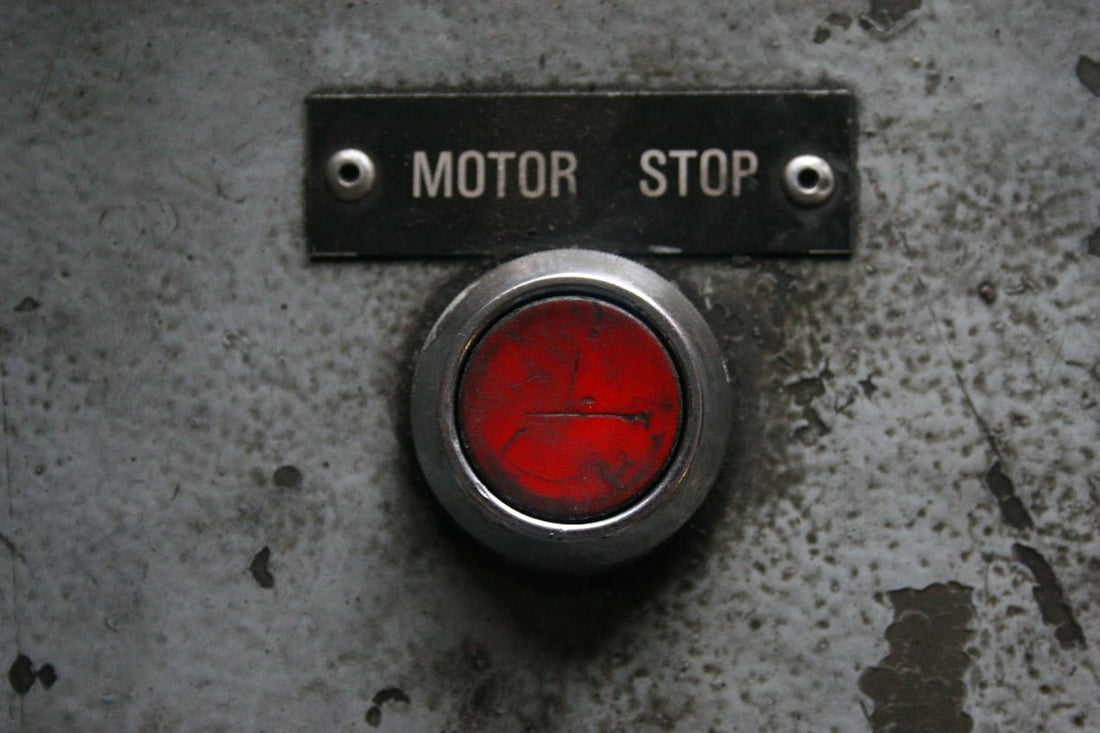 Red motor stop button on a metal panel