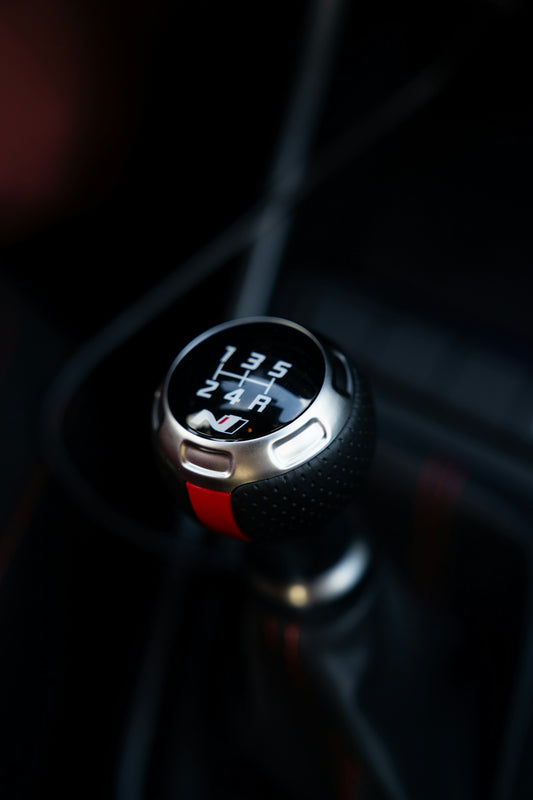 Close-up of a manual car gear shift knob.